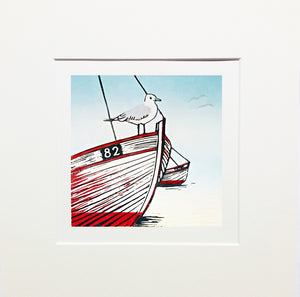 Mounted lino print in blue, red and black ink of seagull perched on beached boat