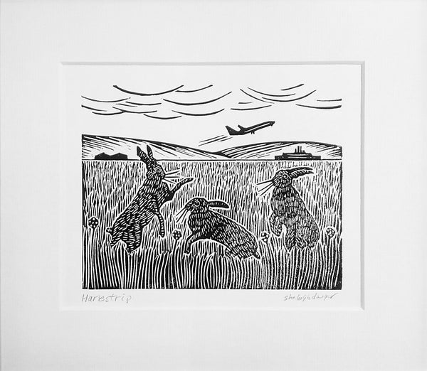 Mounted linocut in black ink of hares playing at airstrip
