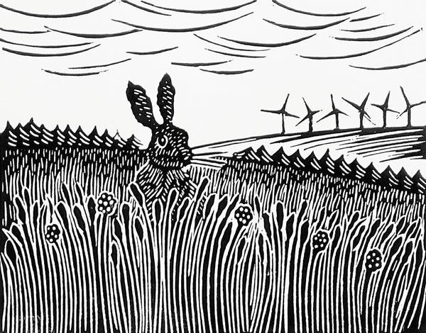 Lino print image in black ink of hare in long grass and wind turbines on distant hill