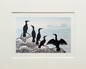 Lino print in black and blue grey ink of cormorants on rocks as cargo ship sails by in the distance