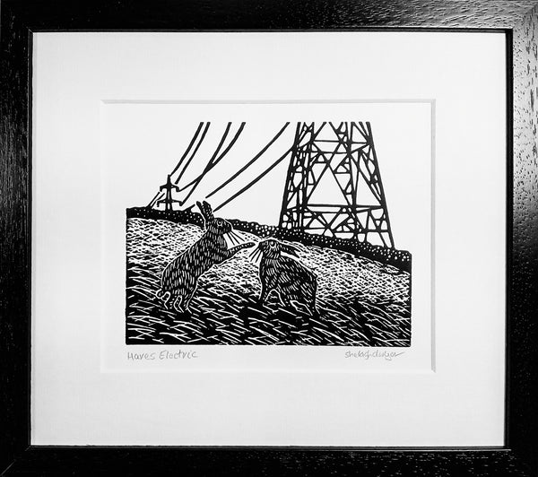 Framed linocut of hares playing in landscape of electric pylons