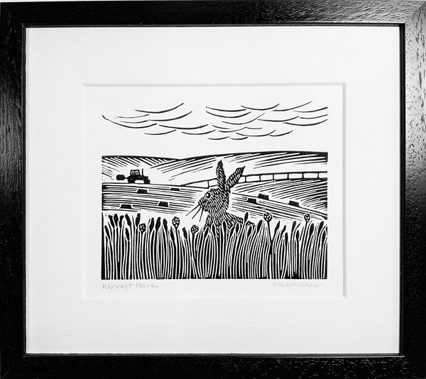 Framed lino print in black ink of hare gazing at tractor working in a field in the distance