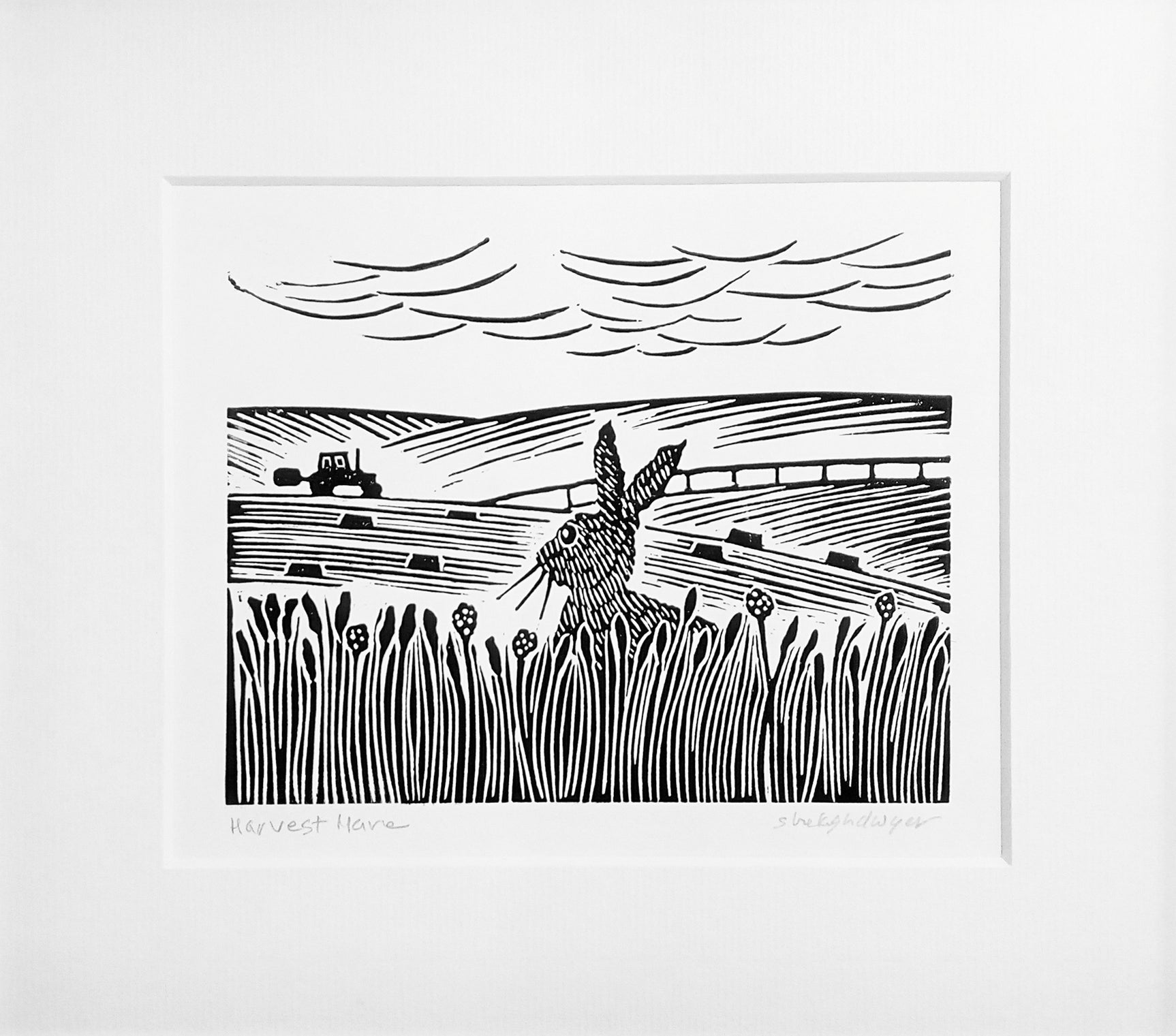 Mounted lino print in black ink of hare gazing at tractor working in a field in the distance